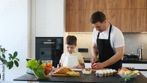 Caucasian man and boy cooking in a contemporary kitchen, chopping vegetables and arranging ingredients on a wooden cutting board