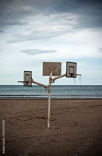 An old and damaged basketball hoop on the beach