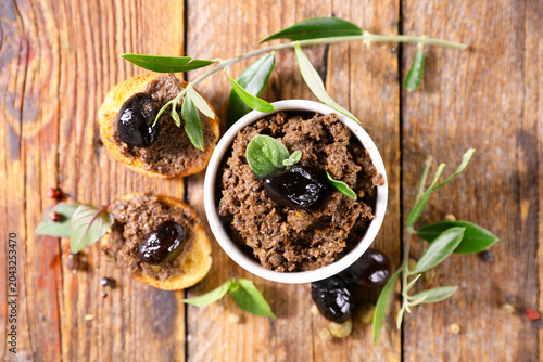 Canvastavla flat lay black olive tapenade in white bowl with crostini and olive branch