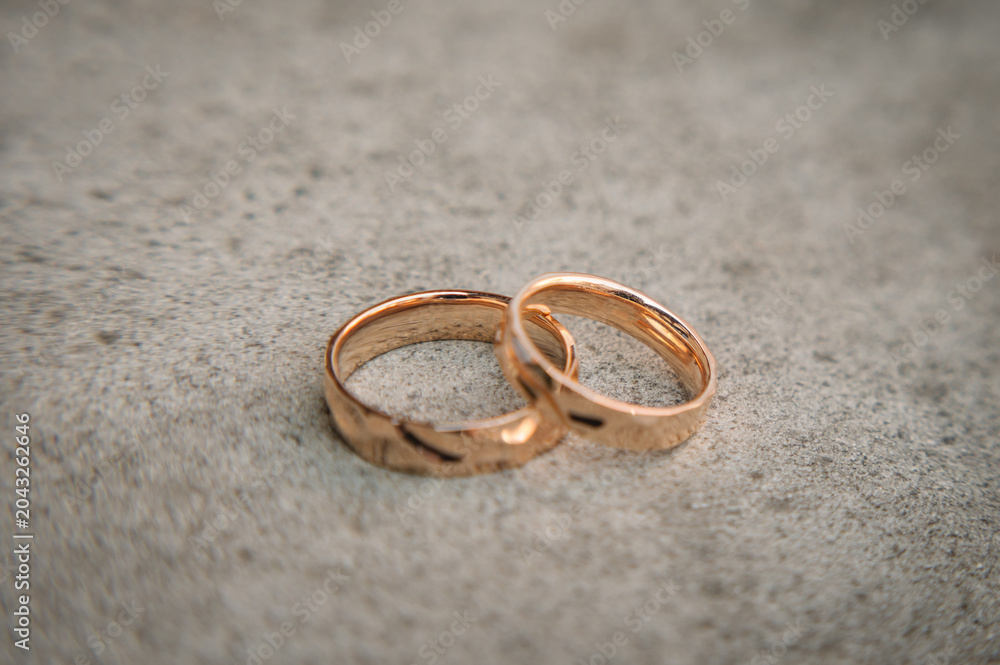 Φωτογραφία Close-up of elegant gold wedding rings on a textured stone surface