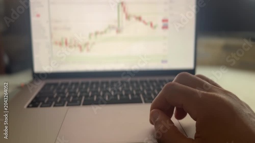 Hand using a trackpad on a laptop as it surveys a trading chart for a commodity