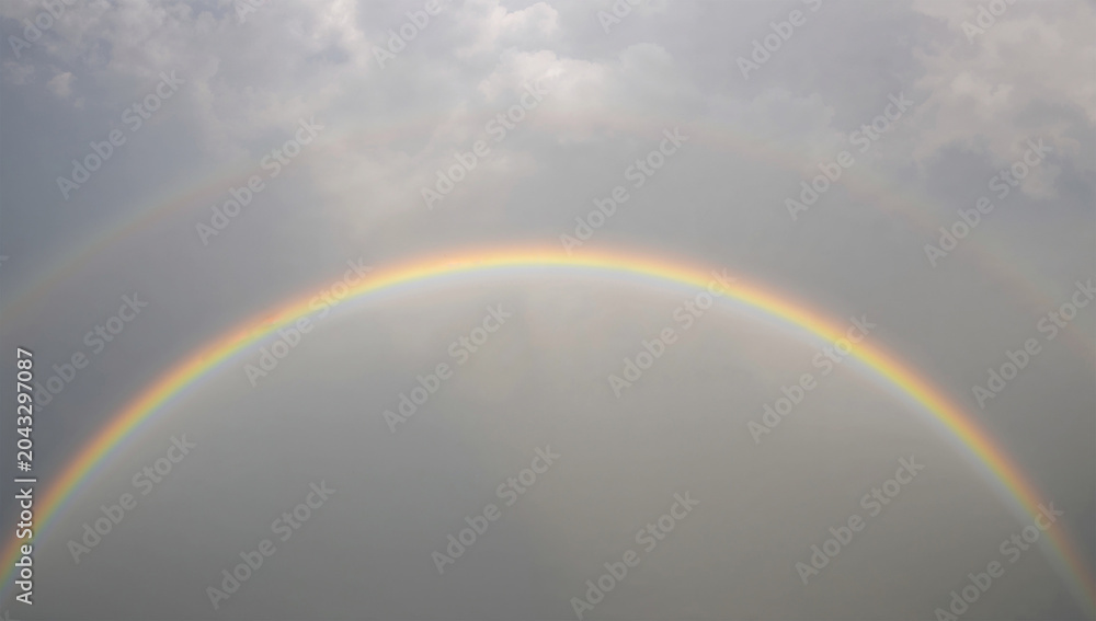 Naklejka premium 雨上がりの空に虹と明るい雲が静かに広がる写真