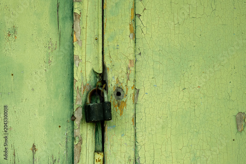 Padlock on Weathered Green Wooden Door with Peeling Paint