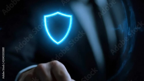 Businessman touching a glowing digital security shield icon, cybersecurity and data protection concept.
