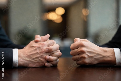 Manos de ejecutivos sobre una mesa de madera, mostrando una actitud de negociación, tensión corporativa o toma de decisiones.