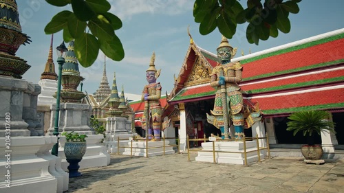 Traditional giant guardian statues at Wat Phra Kaew temple courtyard in Bangkok Thailand with ornate Thai architecture