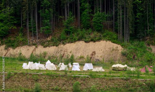 Photos Medieval reenactment camp with white tents set up at the edge of a dense forest