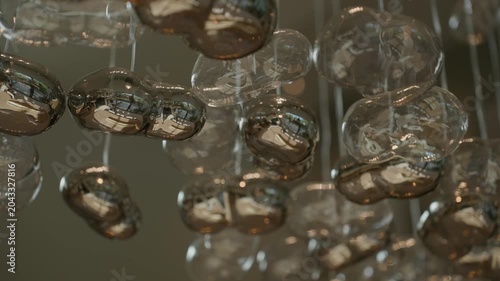 Close view of hanging glass spheres with shiny reflections, soft light fills space and creates calm feeling. Each sphere shows gentle shapes and smooth surface