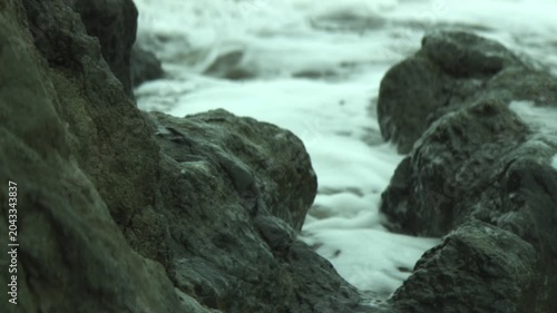 Waves crash against rocks at a beach near Los Angeles, California in the early morning light