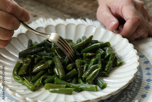 Woman eating cooked green beans. Healthy vegetarian plant based meal