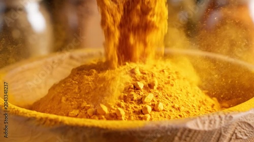 Golden Turmeric Powder Pouring Into Wooden Bowl