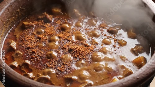 Spices Being Added to Meat Curry in Clay Pot
