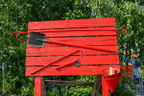 Red wooden fire shield with firefighting tools outdoors