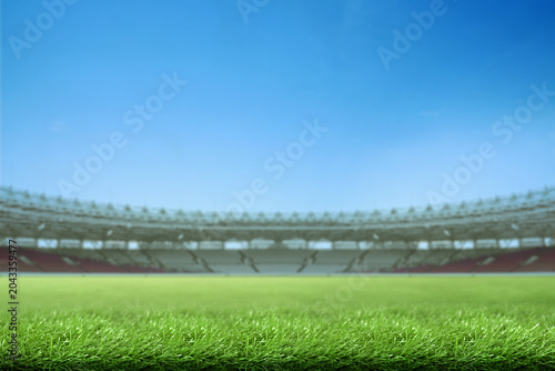Photos Low-angle view of a vibrant green grass field inside a large, empty sports stadi