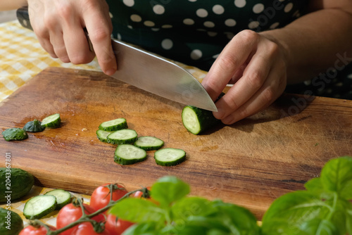Cooking diet summer food. Hands slicing fresh cucumber to make vegetable salad