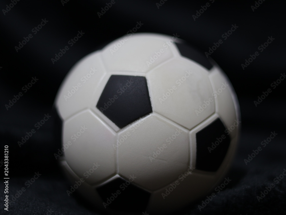 Naklejka premium Una toma de cerca de una pelota o balón de fútbol con luces en un fondo negro con algo de desenfoque 