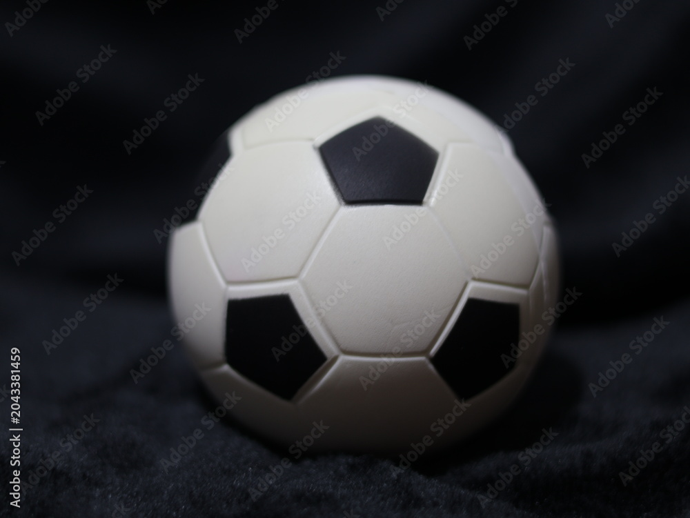 Fototapeta premium Una toma de cerca de una pelota o balón de fútbol con luces en un fondo negro con algo de desenfoque 