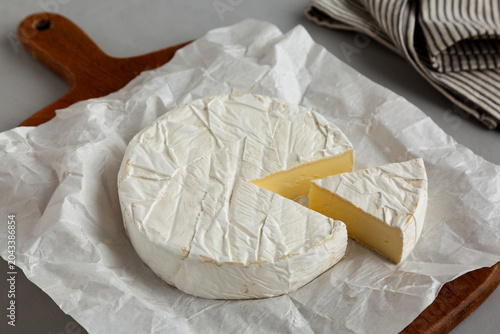 Organic White Brie Cheese on a Wooden Board, side view.