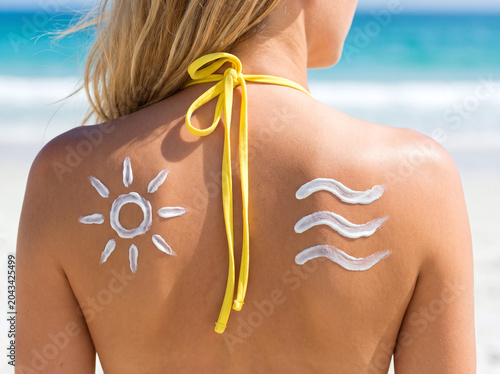 Sunscreen lotion drawn as a sun and waves on a woman's back at the beach