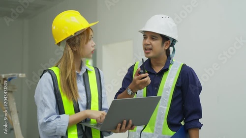 Construction site worker engineer safety vest hard hat inspection teamwork planning communication interior project renovation industrial site supervisor woman man laptop walkie talkie reflective vest