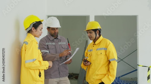 Construction worker team safety helmet yellow jacket inspection document walkie talkie indoor building workplace project discussion planning and safety review
