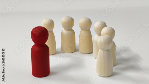 Schilderij op canvas ​Leadership and influence concept with a red wooden figurine standing out in front of a group of white figurines on a plain background