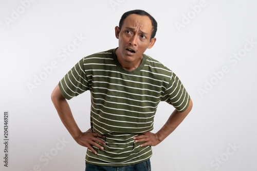 Bild auf Leinwand A man wearing a green shirt with white stripes leans forward with his hands on his hips, appearing tired or exhausted, possibly after physical activity