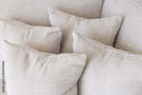 Stack of beige linen fabric cushions with soft folds