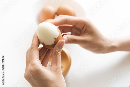 Konstfotografi Protein in food, keto diet asian young woman hand peeling, shelling chicken boiled egg, prepares ingredient for breakfast meal on table at home