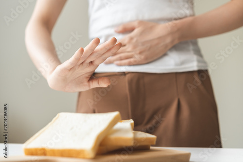 Canvas Print Gluten allergy, asian young woman hand push out, refusing to eat white bread slice on chopping board in food meal at home, girl having a stomach ache