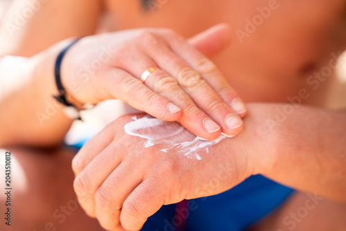 Caucasian man applies SPF sunscreen cream on his hand at a beach resort with close view of skin care and sun protection. Sun safety and skincare lifestyle