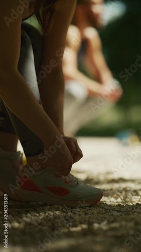 A person ties their running shoe laces, preparing for a workout. This individual gets ready for physical activity in an outdoor setting