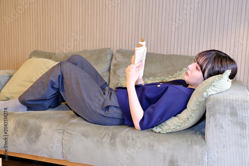 Quadro su tela 癒しの「自分時間」。ソファで寝ころびながら読書に没頭する女性の穏やかなライフスタイルシーン