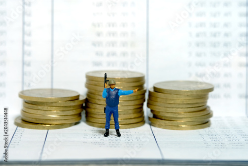 Miniature people toy figure photography. Bank account protection concept. A security officer standing above bank account with golden money coin. Isolated on white background