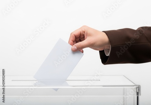 Hand casting a vote into a ballot box isolated on white background