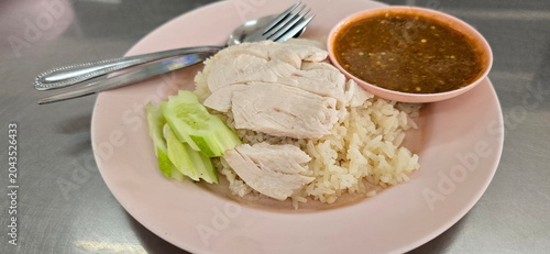  Hainanese chicken rice, Khao Man Gai With chicken topped with fermented soya beans sauce and ginger. Rice cooked in chicken broth and served with spoon-fork and boiled chicken, sliced ​​cucumber. 
