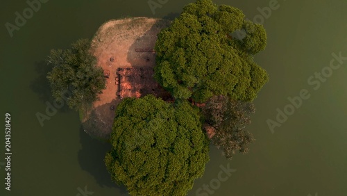 Foto Sukhothai ancient ruins on a small island surrounded by dark water, with lush gr