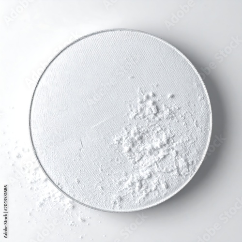 Scattered White Powder Resting on Round Textured Surface in Minimal Studio Setting