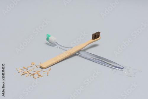 Bamboo and plastic toothbrushes crossed front view eco concept on gray background horizontal
