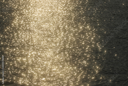 Tableau sur toile Abstract golden bokeh dancing on a dark water surface under summer sunlight