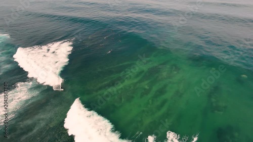 Aerial drone view of surfers, surfing paddling, duck diving, with beautiful blue collars and glass sea