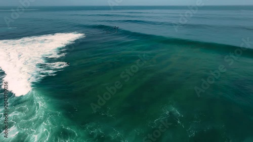 Aerial drone view of surfers, surfing paddling, duck diving, with beautiful blue collars and glass sea