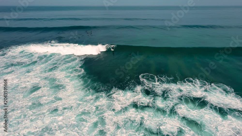Aerial drone view of surfers, surfing paddling, duck diving, with beautiful blue collars and glass sea