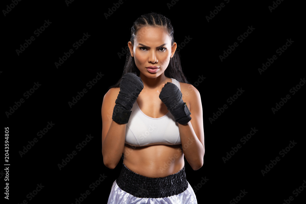 Obraz premium Asian female boxer standing in a fighting stance with black hand wraps looking at the camera on an isolated black background