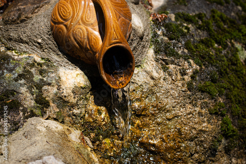 A waterfall in the forest flows from a jug.