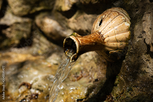 A waterfall in the forest flows from a jug.