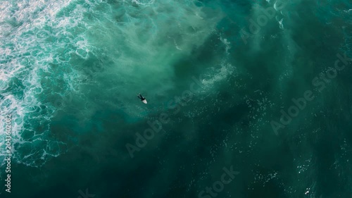 Aerial drone view of surfers, surfing paddling, duck diving, with beautiful blue collars and glass sea
