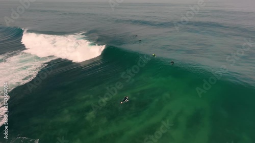 Aerial drone view of surfers, surfing paddling, duck diving, with beautiful blue collars and glass sea