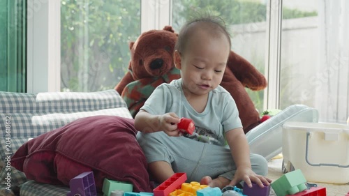 A young child is happily engaged in play with colorful building blocks on a soft surface. The cheerful environment is filled with natural light, showcasing a playful and nurturing space perfect for cr