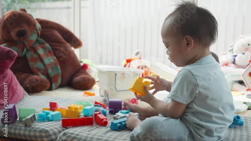 A young child is engaged in play with bright building blocks and toys on a soft surface. This playful scene captures the joy and creativity of early childhood, emphasizing the importance of play in de